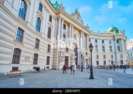 VIENNA, AUSTRIA - 19 FEBBRAIO 2019: L'affollata piazza Michaelerplatz con vista sull'edificio panoramico dell'ala di San Michele del Palazzo Hofburg, deco Foto Stock