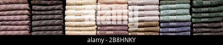 Asciugamani piegati multicolore su scaffali. Vestiti piegati con precisione. Rack di vestiti con caldo. Asciugamani in cotone piegati in modo molto nitoso Foto Stock