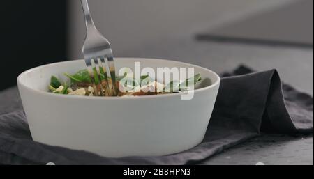 uomo mangia insalata con pomodori kumati e spinaci in ciotola bianca foto ampia Foto Stock