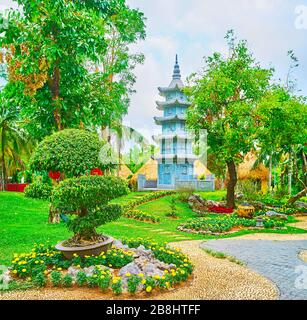 Godetevi il giardino ornamentale della Cina con l'albero del penjing (pun-sai, penzai), i letti di fiori, il prato verde e l'autentica pagoda di pietra sullo sfondo, Rajapruek par Foto Stock