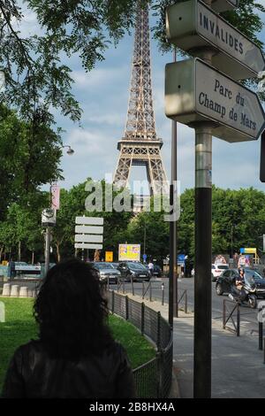 Una scena di strada di Parigi Quai Branly, una vista della Tour Eiffel, gli alberi, una donna a piedi da vecchi cartelli stradali illuminati, Parc Champ de Mars & Invalides; Francia Foto Stock