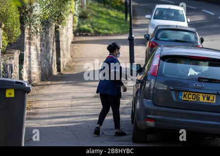 Cardiff, Galles, Regno Unito. 22 marzo 2020. CARDIFF, WALES, REGNO UNITO - 22 MARZO 2020 - un lavoratore del NHS che indossa una maschera facciale si avvicina a un'automobile dopo una visita domestica a Cardiff mentre il coronavirus accelera nel Regno Unito. Credit: Mark Hawkins/Alamy Live News Foto Stock