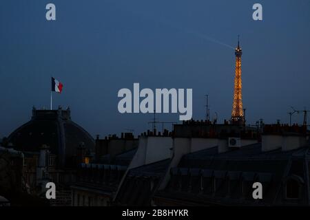 Notte a Parigi, una bandiera francese vola sopra la camera del Cercle National des armées, con un fascio di luce illuminato sulla Torre Eiffel contro il cielo blu profondo Foto Stock