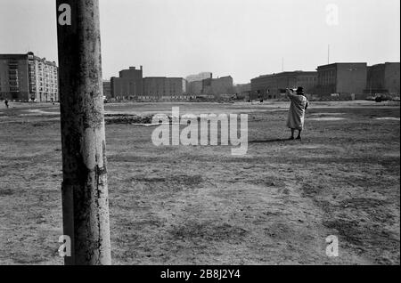 Una donna che guarda agli appartamenti nella ex Germania Est da Potsdamer Platz, dove il muro era stato precedentemente gestito. Il Muro di Berlino era una barriera costruita dalla Repubblica democratica tedesca (RDT, Germania orientale) a partire dal 13 agosto 1961, che ha completamente tagliato Berlino Ovest dalla Germania Est circostante e da Berlino Est. Il Muro è stato aperto il 9. Novembre 1989 consentire la libera circolazione delle persone da est a ovest. Foto Stock