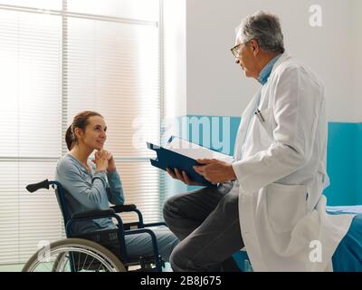 Medico sicuro che visita un paziente paraplegico in sedia a rotelle presso l'ospedale Foto Stock