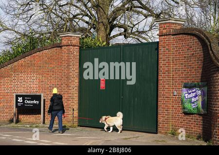 Un camminatore per cani passa l'ingresso per Osterley Park and House a Isleworth, Londra, dopo che il National Trust ha annunciato di aver chiuso tutti i suoi parchi e giardini in tutto il Regno Unito fino a nuovo avviso. Foto Stock