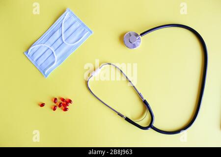Stetoscopio medico, stetoscopio e pillole rosse su sfondo giallo. Pillole e trattamenti. Foto Stock