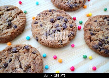 biscotti al cioccolato su sfondo di legno, biscotti al cioccolato, biscotti al legno, biscotti fatti in casa al cioccolato, biscotti con spruzzette colorate Foto Stock