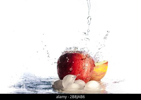 Mela rossa in ruscelli di acqua. Spruzzi d'acqua isolati su bianco. Frutta fresca. Foto Stock