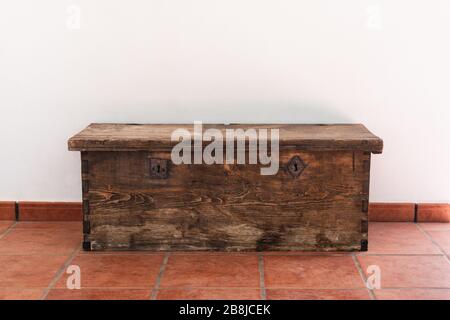 Vecchio petto di legno con due serrature di metallo su fondo bianco e pavimento rosso Foto Stock