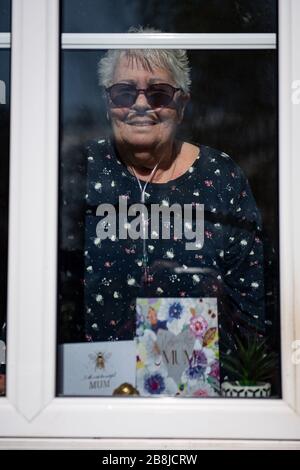 Olive Trotman, 76 anni, è visitata nel giorno della Madre da suo figlio Mark Trotman. L'oliva soffre di malattia polmonare ostruttiva cronica (BPCO) ed enfisema, e sta prendendo la precauzione di comunicare ad una distanza di sicurezza o attraverso una finestra di vetro, per limitare la diffusione potenziale di coronavirus. Data foto domenica 22 marzo 2020. Vedi la storia PA SALUTE Coronavirus. Il credito della foto dovrebbe leggere: Jacob King/PA Wire Foto Stock