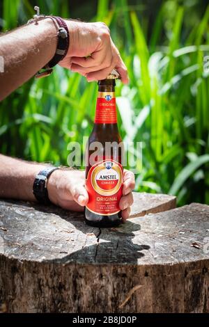 Un uomo che apre una bottiglia di birra Amstel nel paese Foto Stock