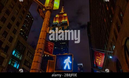 Vista notturna dell'Empire state Building dalla prospettiva inferiore di fronte a un semaforo. Foto Stock