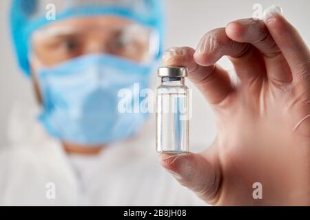 Mano del medico contenente un flaconcino di liquido limpido per iniezione. Foto Stock