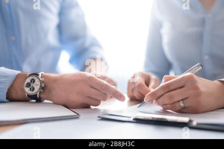 Uomini d'affari che negoziano un contratto. Mani umane che lavorano con i documenti alla scrivania e firmano il contratto. Foto Stock