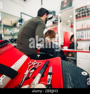 il parrucchiere taglia i capelli con le forbici sul cliente soddisfatto della corona nel salone professionale di parrucchiere Foto Stock