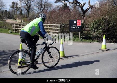 Un ciclista passa l'ingresso bloccato a Croome nel Worcestershire dopo che il National Trust ha annunciato di aver chiuso tutti i suoi parchi e giardini in tutto il Regno Unito fino a nuovo avviso. Foto Stock