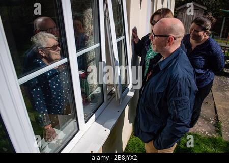 RITRASMESSO AGGIUNGENDO LUOGO Olive Trotman, 76, è visitato il giorno della madre da suo figlio Mark Trotman a Napton sulla collina, Warwickshire. L'oliva soffre di malattia polmonare ostruttiva cronica (BPCO) ed enfisema, e sta prendendo la precauzione di comunicare ad una distanza di sicurezza o attraverso una finestra di vetro, per limitare la diffusione potenziale di coronavirus. Foto Stock