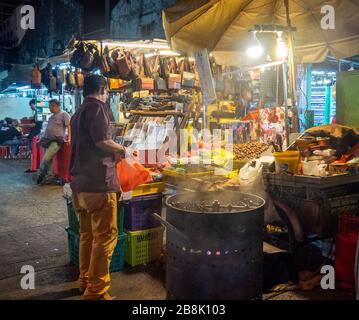 Fornitore che arrostirà le castagne al mercato di Petaling Street di notte Kuala Lumpur Malesia. Foto Stock