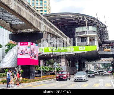 Gli acquirenti che attraversano Jalan Sultan Ismail sotto Bukit Bintang KL stazione della linea monorotaia Kuala Lumpur Malesia. Foto Stock