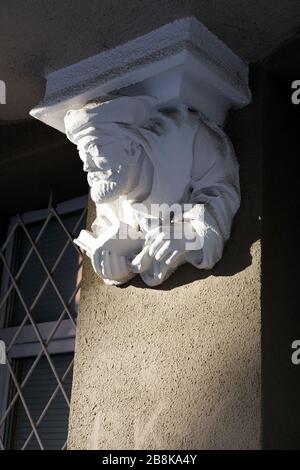 Elementi di decorazioni architettoniche di vecchi edifici, figura di gesso bianco e volto dell'uomo. Un uomo con gli occhiali tiene un libro. L'elemento di decoratio Foto Stock
