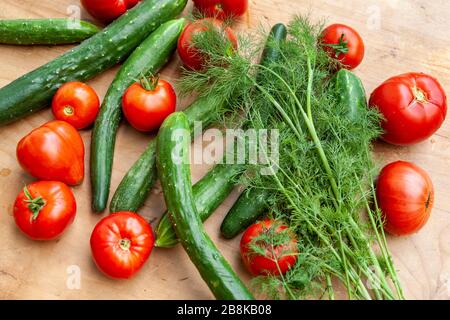 Verdure crude, pomodori, cetrioli e aneto, cibo fresco su tavola di legno Foto Stock