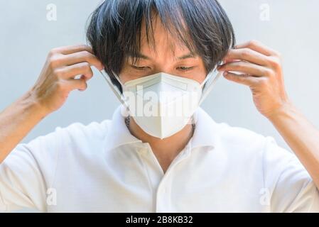 Un uomo asiatico indossa la maschera N95 Foto Stock