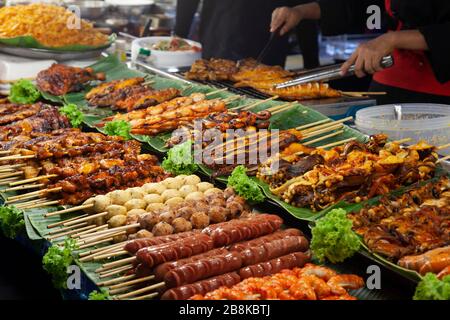 Esposizione di cibi alla griglia o alla brace su spiedini per la vendita nel mercato locale di Street food, esposto su foglia di banana a Bangkok, Thailandia Foto Stock