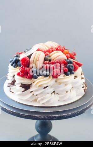 Torta Pavlova con fragole fresche, ciliegie, mirtilli e lamponi, cioccolato fuso e panna montata. Foto Stock