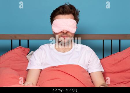 Uomo maturo caucasico con maschera dorata rosa che giace a letto da solo. Studio di ripresa Foto Stock