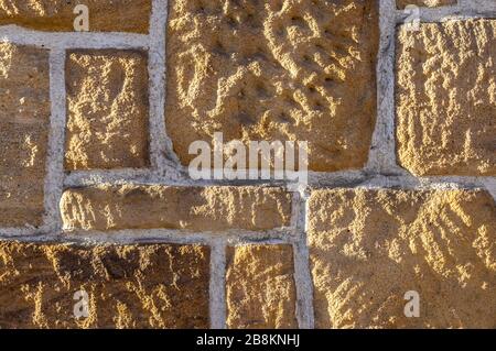 Muro di arenaria, in mattoni con pietra rustica affilata di diverse dimensioni e giunti bianchi Foto Stock