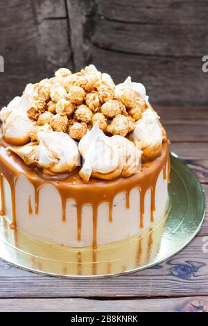 Torta al caramello salata fatta in casa con salsa al caramello e popcorn al caramello su sfondo di legno Foto Stock