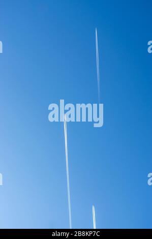 Guardando verso l'alto nel cielo blu e nuvoloso con 3 aerei con contrasti che volano paralleli e sfalsati nella stessa direzione Foto Stock