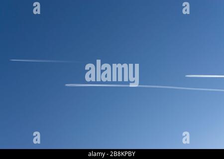 Guardando verso l'alto nel cielo blu e nuvoloso con 3 aerei con contrasti che volano paralleli e sfalsati nella stessa direzione Foto Stock