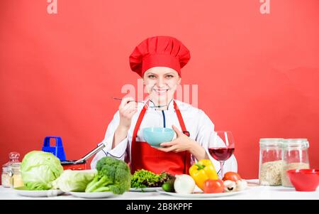 donna in cappello da cuoco. chef professionista su sfondo rosso. donna felice che cucinano cibi sani secondo la ricetta. cibo biologico e vegetariano. Casalinga, menu del ristorante. Dieting. Chi si preoccupa della dieta. Foto Stock