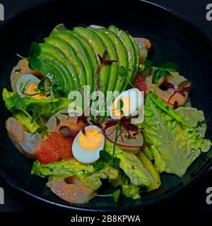 insalata con avocado e gamberi in ciotola, vista dall'alto, spazio per le copie, sfondo nero Foto Stock