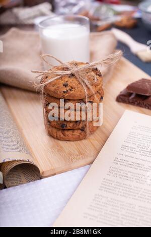 Biscotti farinata d'avena con gocce di cioccolato in una pila con un bicchiere di latte Foto Stock