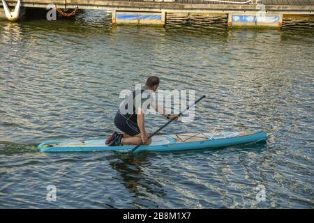 SWANSEA, GALLES - LUGLIO 2018: Persona in ginocchio a bordo di una pagaia sul fiume Tawe vicino al porto turistico di Swansea Foto Stock