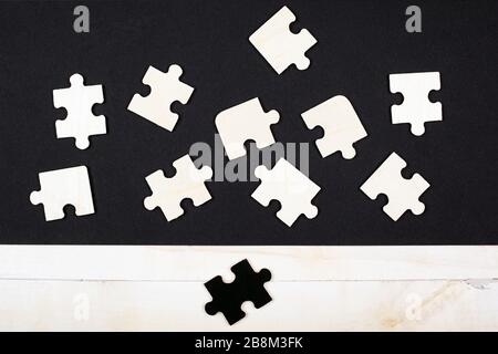 puzzle in legno bianco su sfondo nero e un puzzle nero su sfondo bianco primo piano vista dall'alto. White Crow antisociale diversa leadership sk Foto Stock