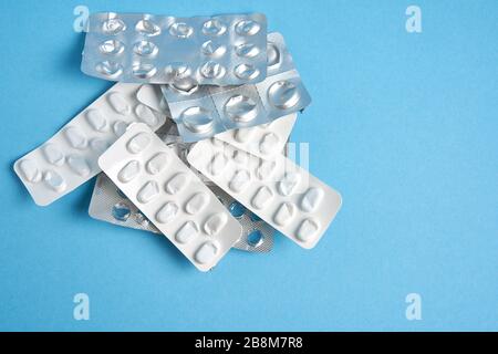 Blister vuoti usati da compresse color argento e bianco e pillole si trovano su sfondo medico blu. Concetto farmaceutico Salute cura e medicina. Fre Foto Stock