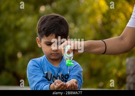 Bambino indiano che usa sanitizer per la protezione dal virus della corona Foto Stock