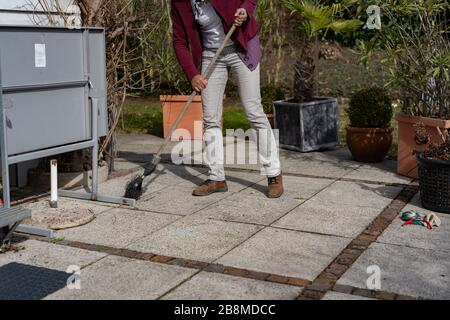 Donna che puliscono fogliame sulla terrazza in primavera. Foto Stock