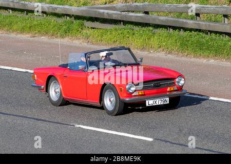 1975 70s Red Triumph TR6; traffico veicolare, trasporto, veicoli in movimento, veicoli, Strade, motori, automobilismo sull'autostrada M6 Foto Stock