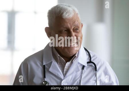 Ritratto di testa di terapista anziano in uniforme di cappotto bianco in interni Foto Stock
