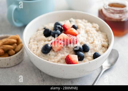 Ciotola di porridge con i berries estivi freschi in ciotola. Concetto di dieta alimentare pulita. Farinata d'avena con Berries Foto Stock