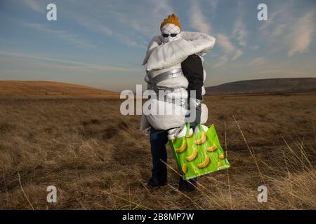 Perthshire Hills, Regno Unito. 22 marzo 2020. Nella foto: Immagine concettuale di una persona che va a lunghezze estreme per autoisolarsi nel mezzo del nulla che trasporta l'articolo più ricercato nel mondo della carta igienica, mentre avvolto in casa ha fatto dispositivi di protezione personale. Credit: Colin Fisher/Alamy Live News Foto Stock