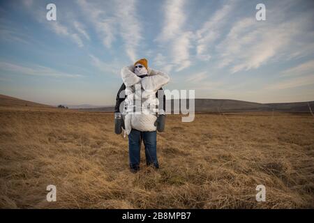 Perthshire Hills, Regno Unito. 22 marzo 2020. Nella foto: Immagine concettuale di una persona che va a lunghezze estreme per autoisolarsi nel mezzo del nulla che trasporta l'articolo più ricercato nel mondo della carta igienica, mentre avvolto in casa ha fatto dispositivi di protezione personale. Credit: Colin Fisher/Alamy Live News Foto Stock