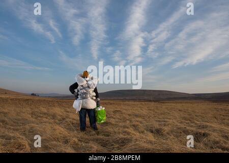 Perthshire Hills, Regno Unito. 22 marzo 2020. Nella foto: Immagine concettuale di una persona che va a lunghezze estreme per autoisolarsi nel mezzo del nulla che trasporta l'articolo più ricercato nel mondo della carta igienica, mentre avvolto in casa ha fatto dispositivi di protezione personale. Credit: Colin Fisher/Alamy Live News Foto Stock