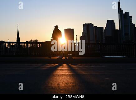 22 marzo 2020, Hessen, Francoforte sul meno: Una coppia attraversa il ponte di zattera al tramonto nella città bancaria. In risposta alla diffusione del coronavirus, alcuni stati federali hanno limitato la vita pubblica. Foto: Arne Dedert/dpa Foto Stock