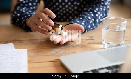 Primo piano giovane donna indiana che prende le pillole dalla bottiglia Foto Stock